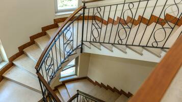 A spiral staircase with a wooden handrail and black metal balusters, leading to an upper floor.