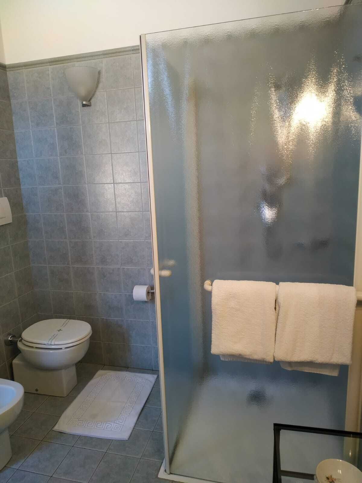 Un baño con inodoro, cabina de ducha y barra para toallas.