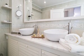 Une salle de bain avec deux grands lavabos blancs, un miroir et un porte-serviettes.