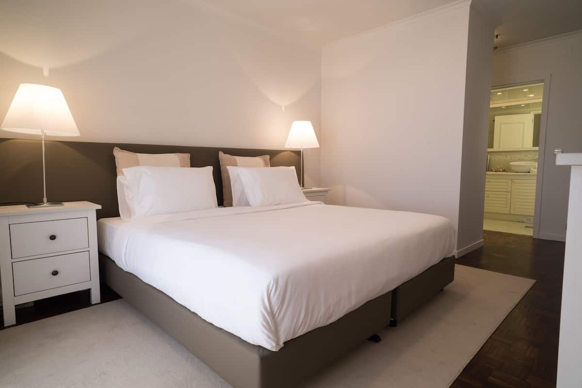 Ein modernes Schlafzimmer mit einem großen Bett, zwei Nachttischen und einem Beistelltisch.