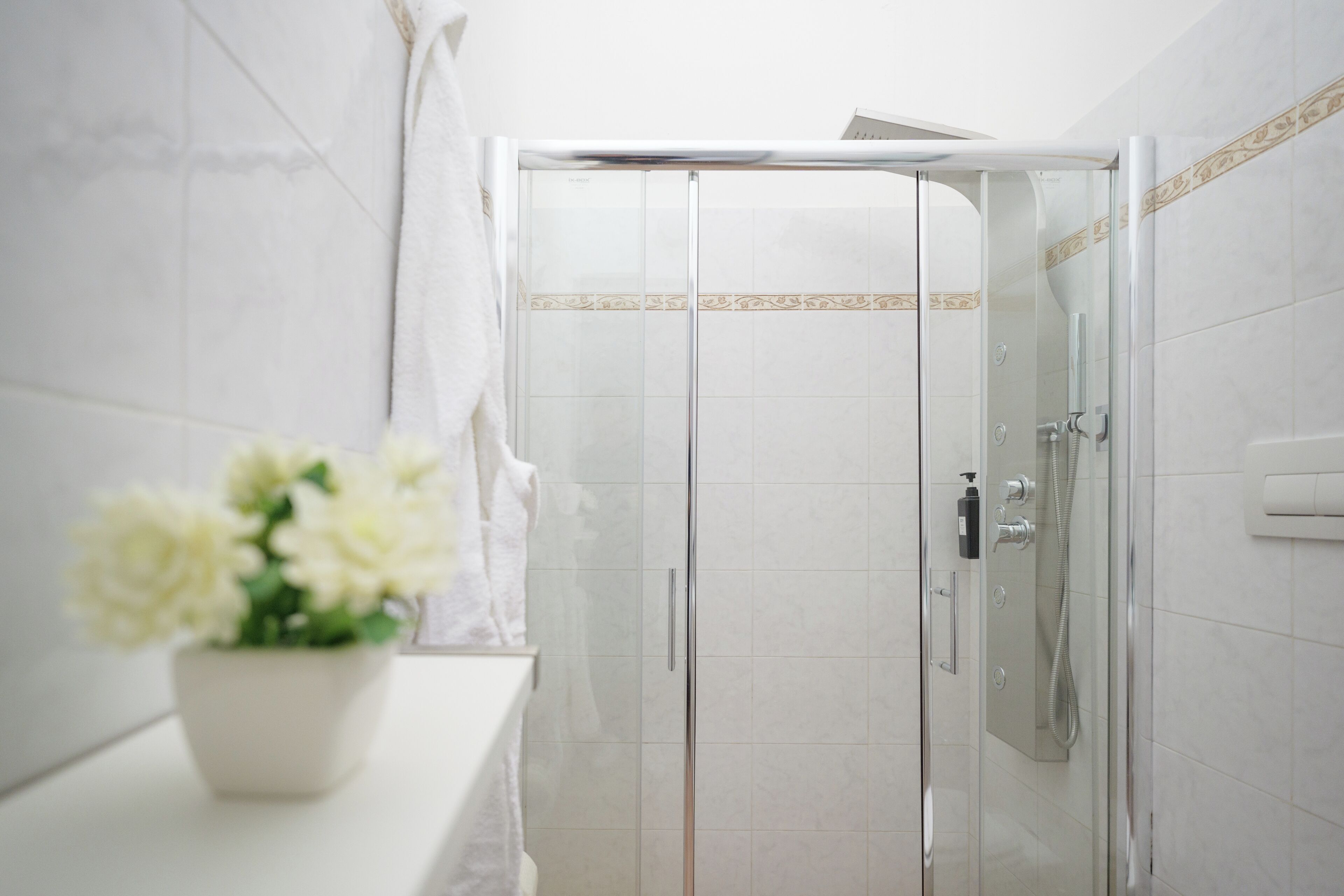 A modern bathroom with a glass shower enclosure, a white sink, and a potted plant.