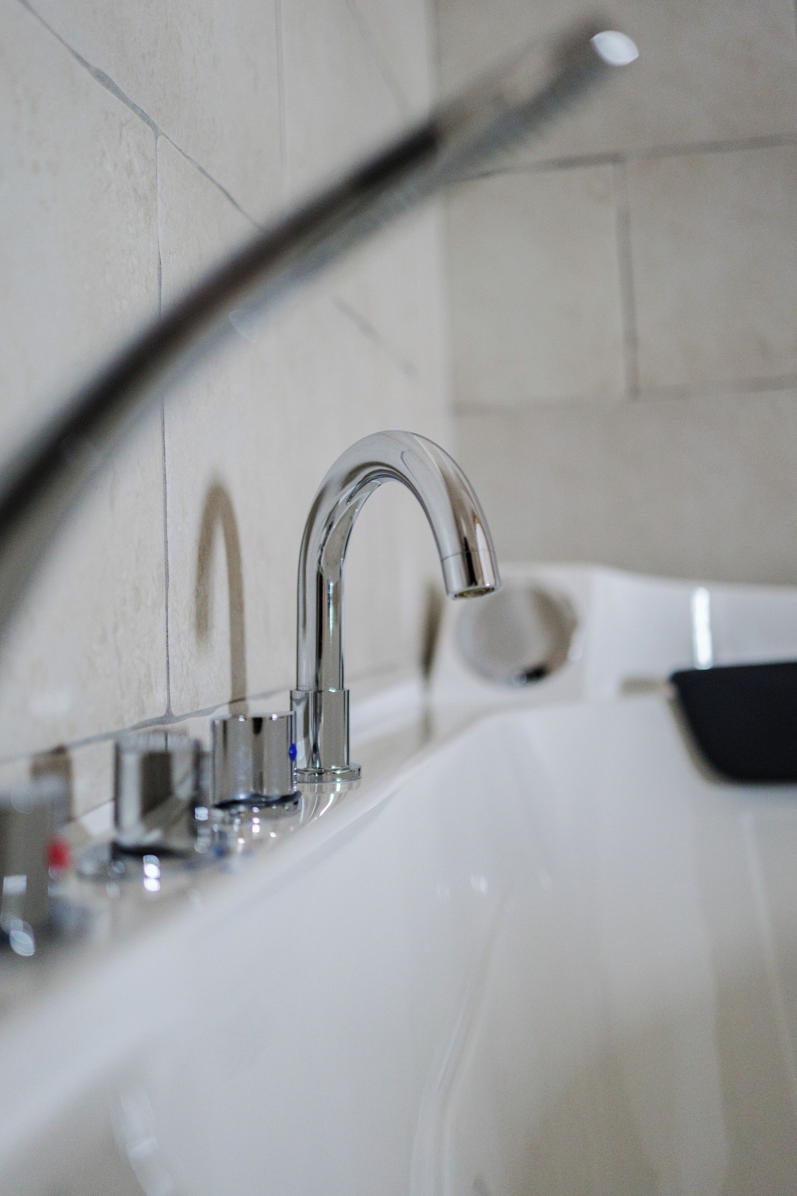 Un bagno moderno con un rubinetto cromato, un lavandino bianco e un box doccia in vetro.