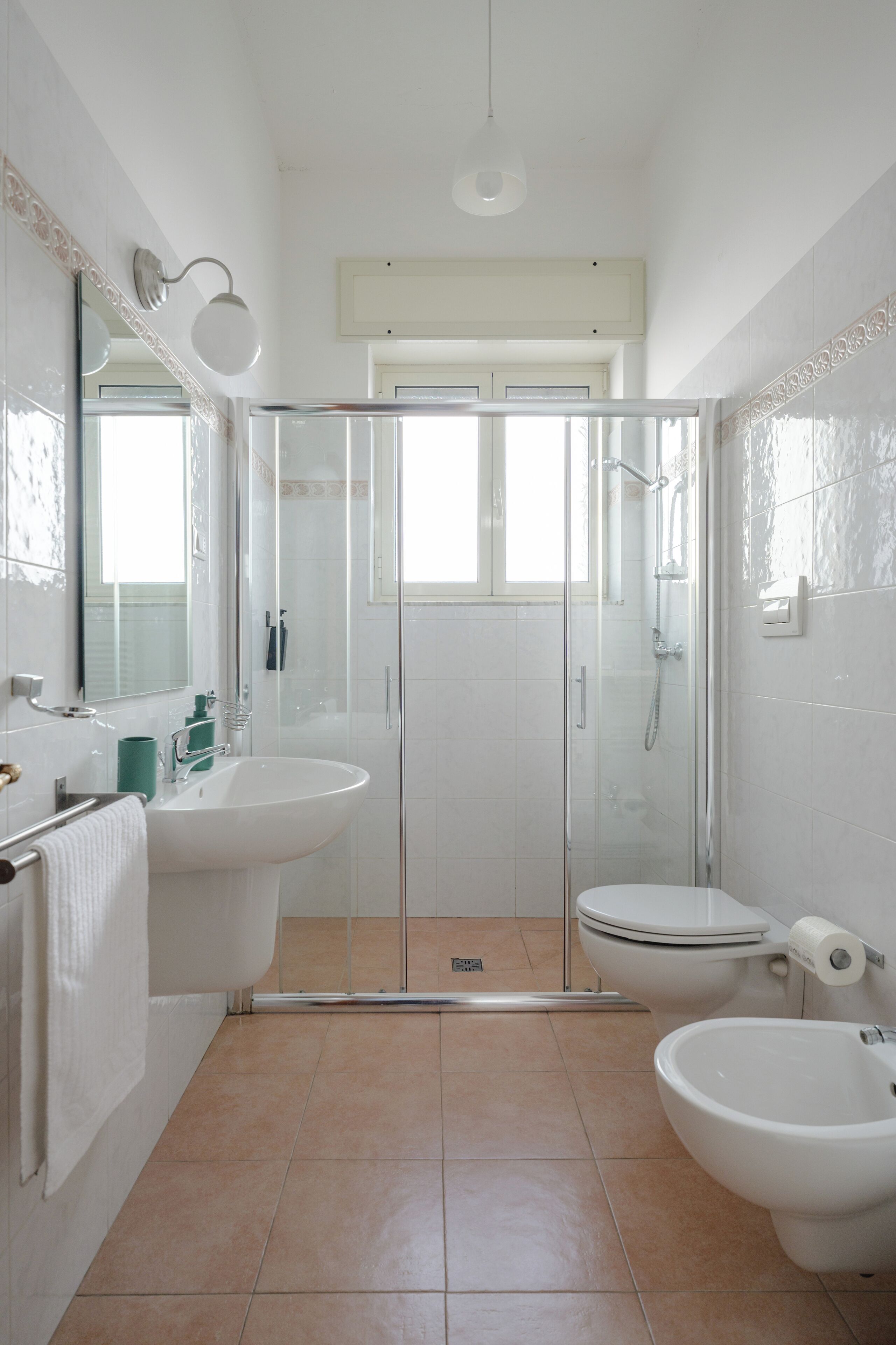 Een badkamer met een wastafel, toilet, bidet en douchecabine.