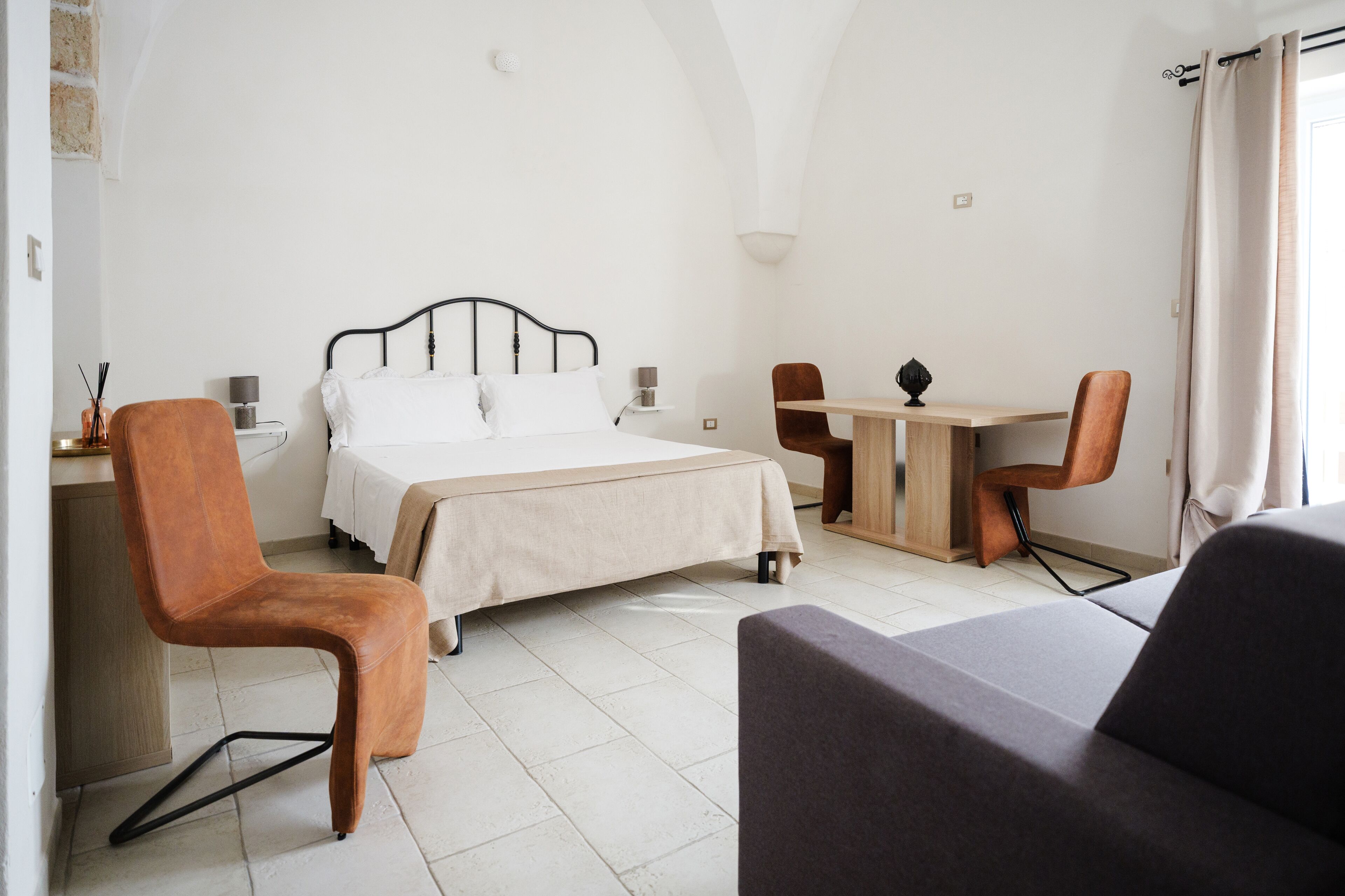A room with a bed, a desk, two chairs, and a sofa.
