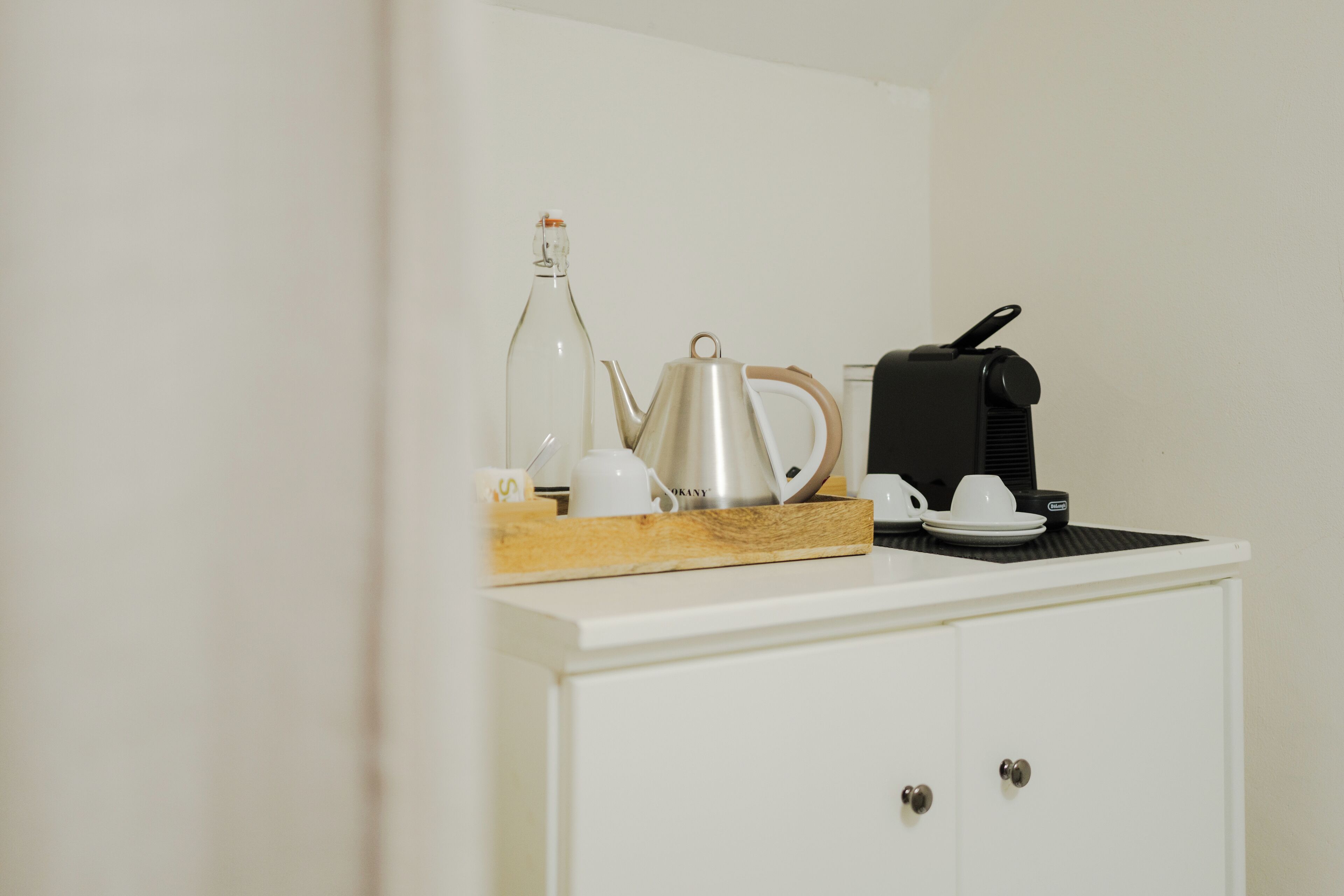 Eine Küchenzeile mit einer Kaffeemaschine, einem Wasserkocher und einer Flasche auf der Arbeitsfläche.
