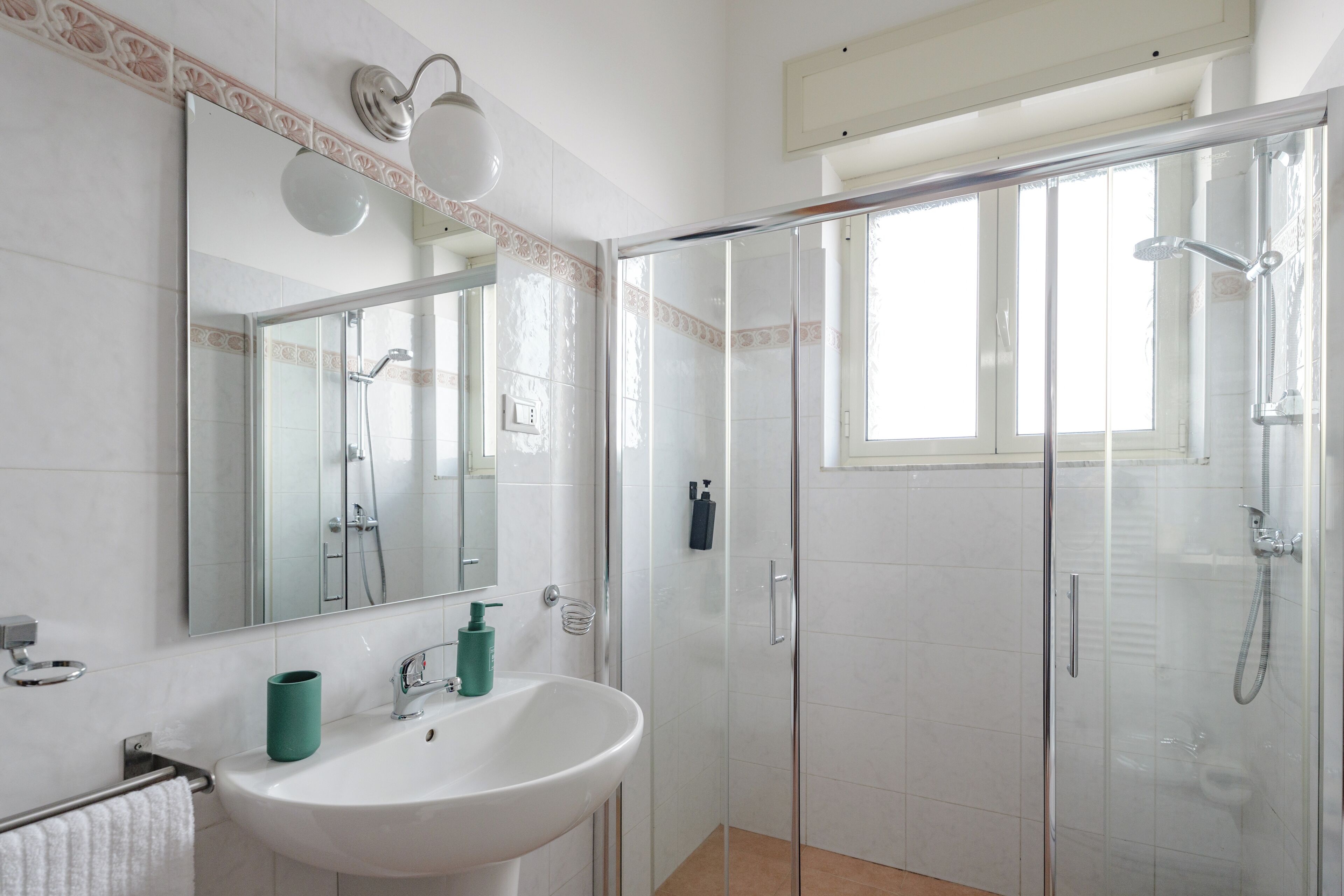 Une salle de bain moderne avec une douche à parois de verre, un lavabo blanc et un grand miroir.
