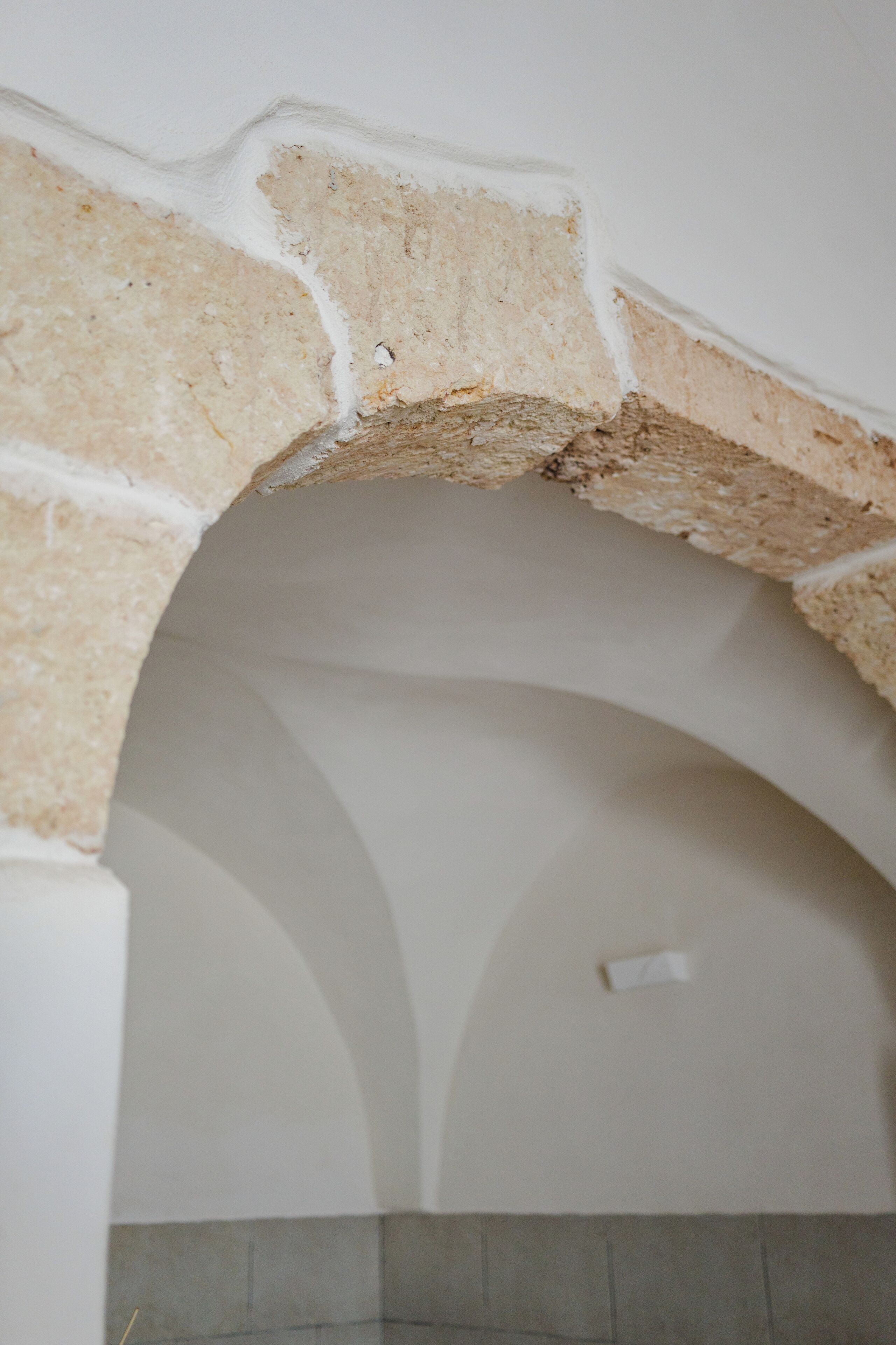 Ein steiner Torbogen mit Fliesenboden.