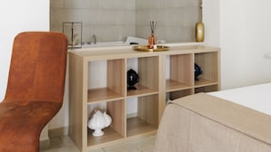 Un baño moderno con un arco de piedra, un tocador de madera, un lavamanos y una silla.
