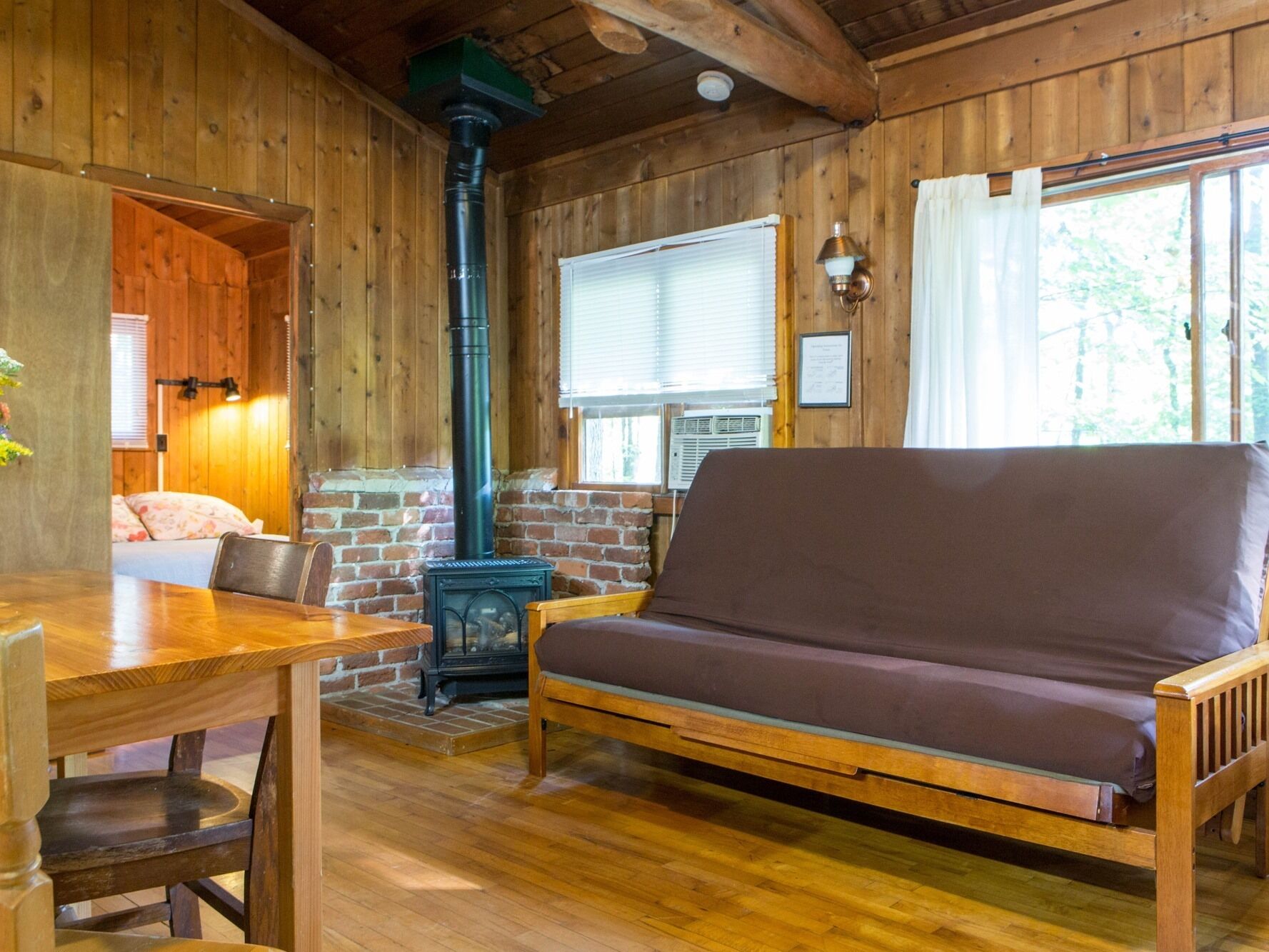 Interior acogedor de una cabaña con paredes de madera, un sofá, una mesa y una chimenea.