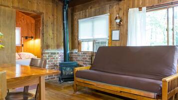 Interior acogedor de una cabaña con paredes de madera, un sofá, una mesa y una chimenea.
