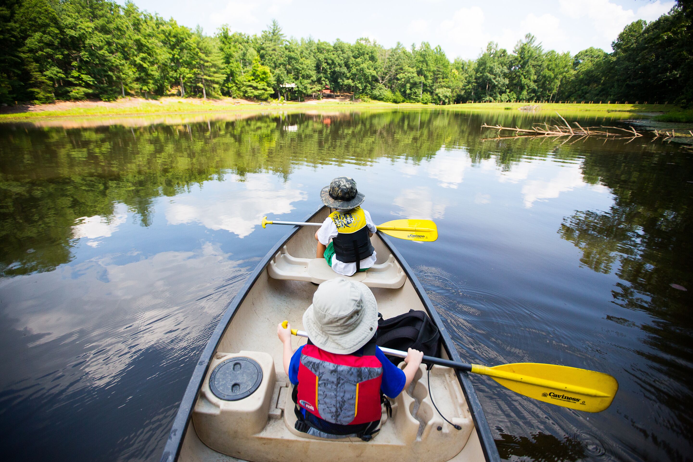 A canoe on a calm lake with trees in the background.