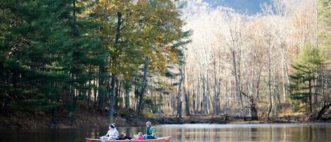 A rowboat on a calm lake surrounded by dense forest.