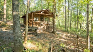 A rustic cabin in a forest with a porch and a deck. - Montfair Resort Farm (Crozet)