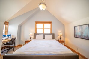 Cozy retreat with a large bed, desk, and window offering a peaceful atmosphere.