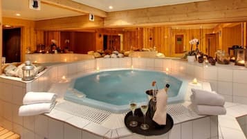 Relax in a serene hot tub surrounded by candles and plush towels.