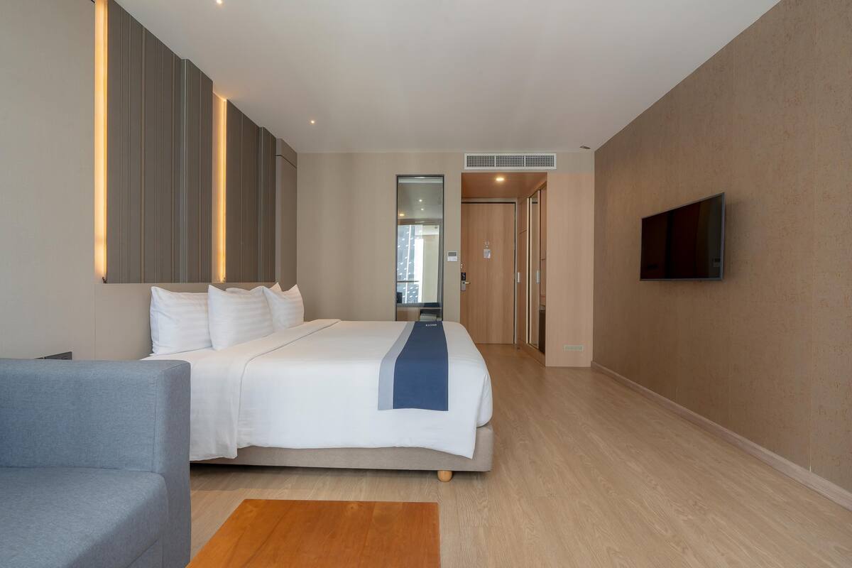 Een moderne hotelkamer met een groot bed, een flatscreen televisie aan de wand en een houten vloer.