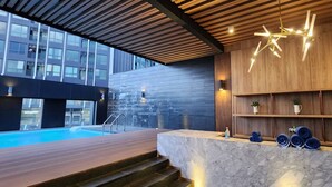 Een modern binnenzwembad met een houten terras, een marmeren receptiebalie en een houten wand met planken.