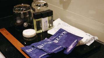 Una encimera de baño con artículos de aseo, como un gorro de ducha, una botella de loción y un tubo de crema.