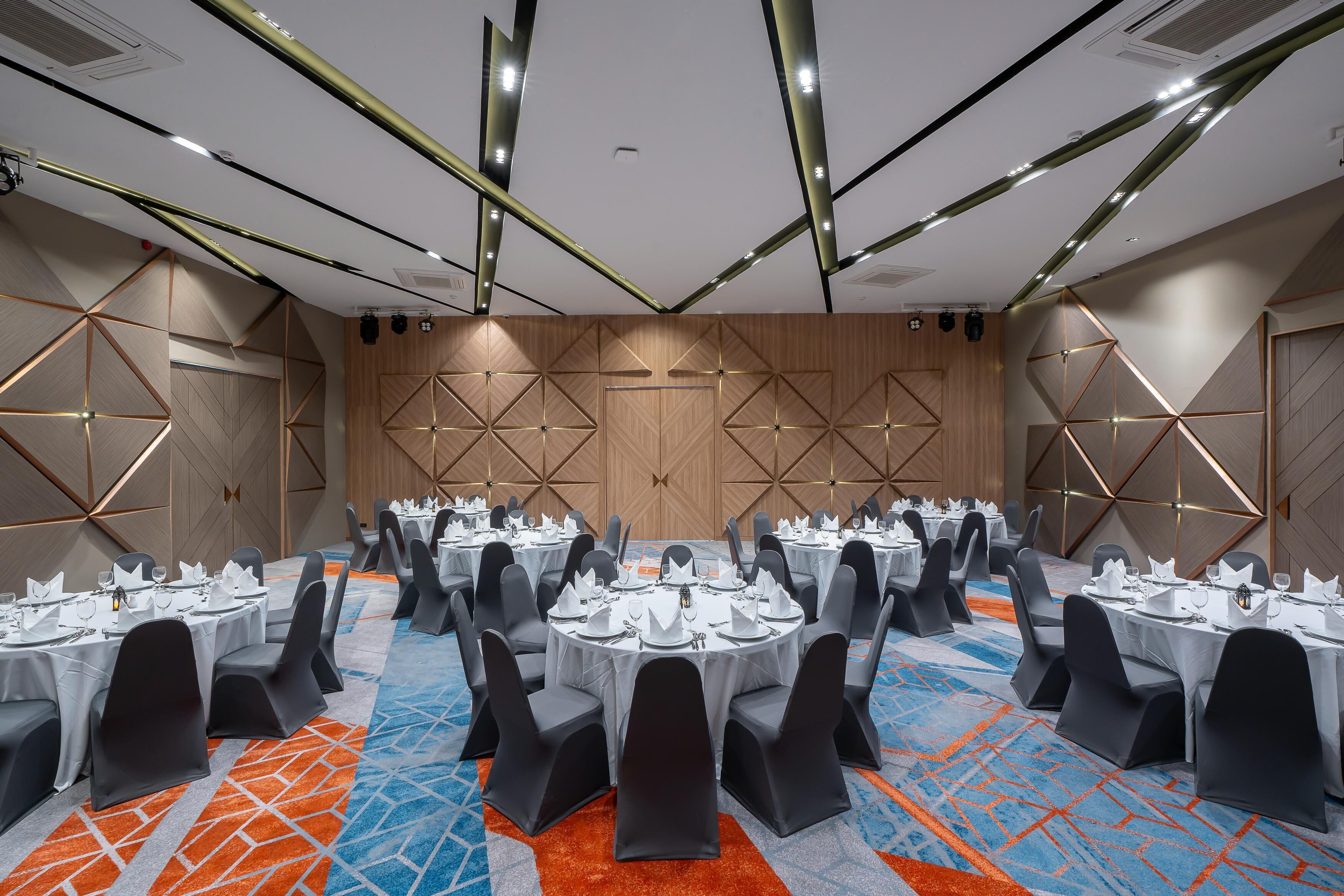 A conference room with round tables, black chairs, and a patterned carpet.