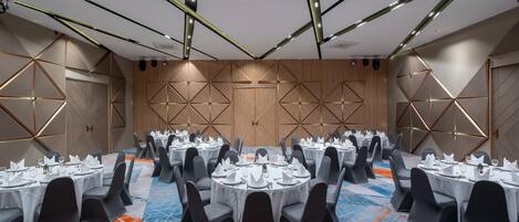 A conference room with round tables, black chairs, and a patterned carpet.
