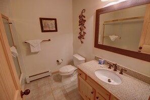 A bathroom with a toilet, sink, and mirror.