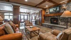 A spacious lobby with leather sofas, a wooden coffee table, a stone fireplace, and a framed picture of an eagle. - Lone Eagle 3000 by SummitCove Vacation Lodging (Keystone)