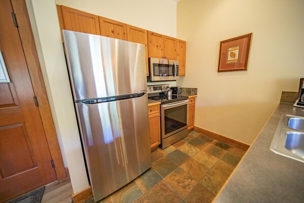 A kitchen with wooden cabinets, stainless steel appliances, and a tiled floor.