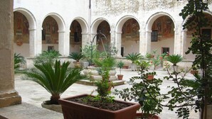 A courtyard with arched walkways, potted plants, and a fountain. - Casina dei Nonni (Carpignano Salentino)