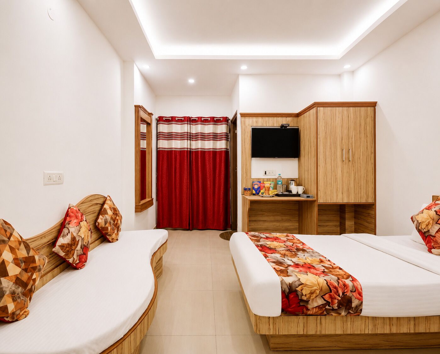 A hotel room with two beds, a desk with a TV, a wardrobe, and a bathroom with a red curtain.