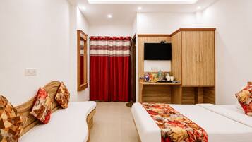 A hotel room with two beds, a desk with a TV, a wardrobe, and a bathroom with a red curtain.