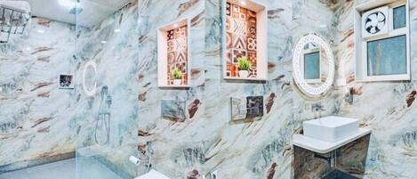 Un bagno con pareti in marmo, due servizi igienici, un lavandino, una ventola a soffitto e pannelli decorativi.