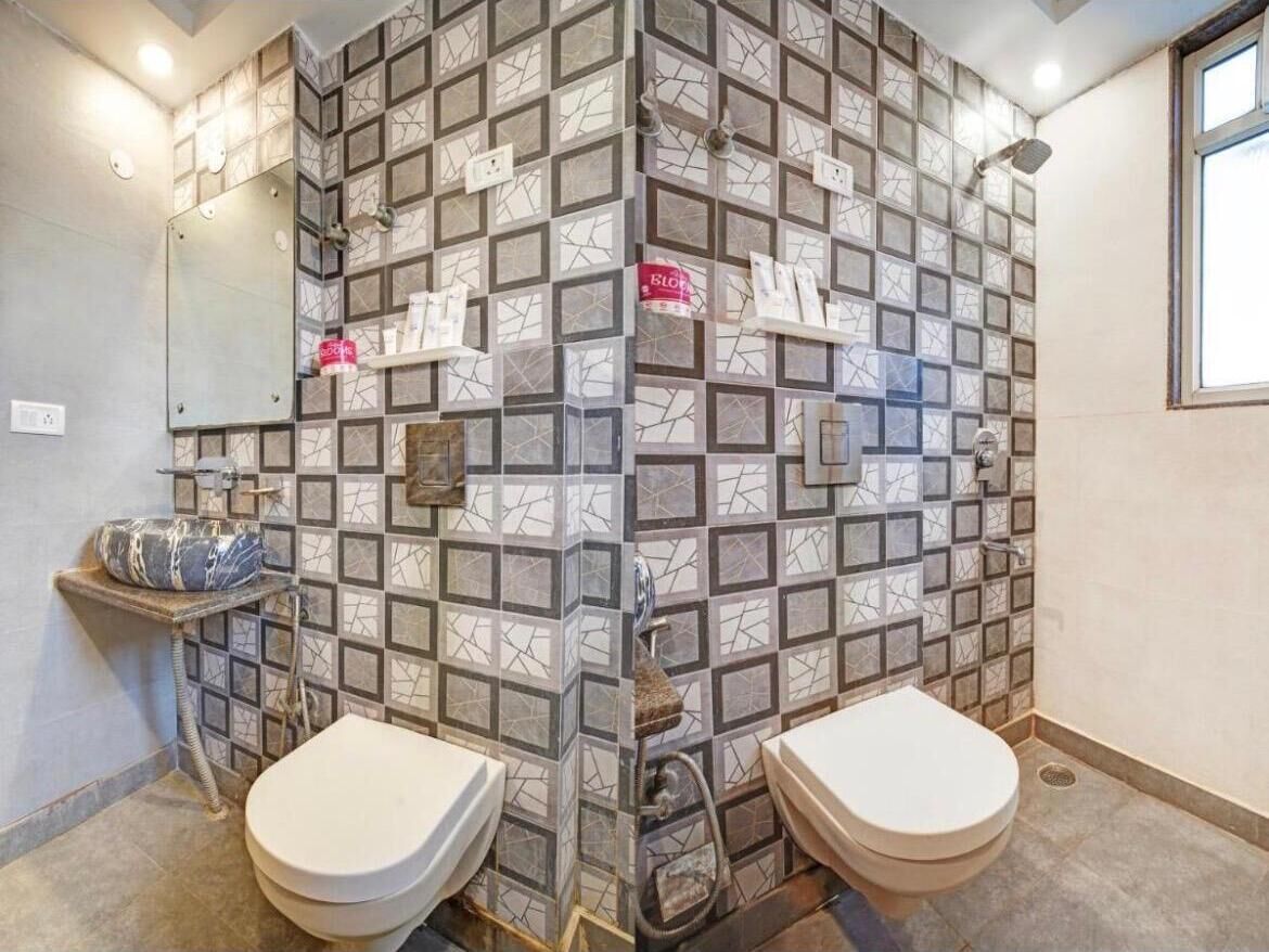 A bathroom with two toilets, a shower, and a mirror.