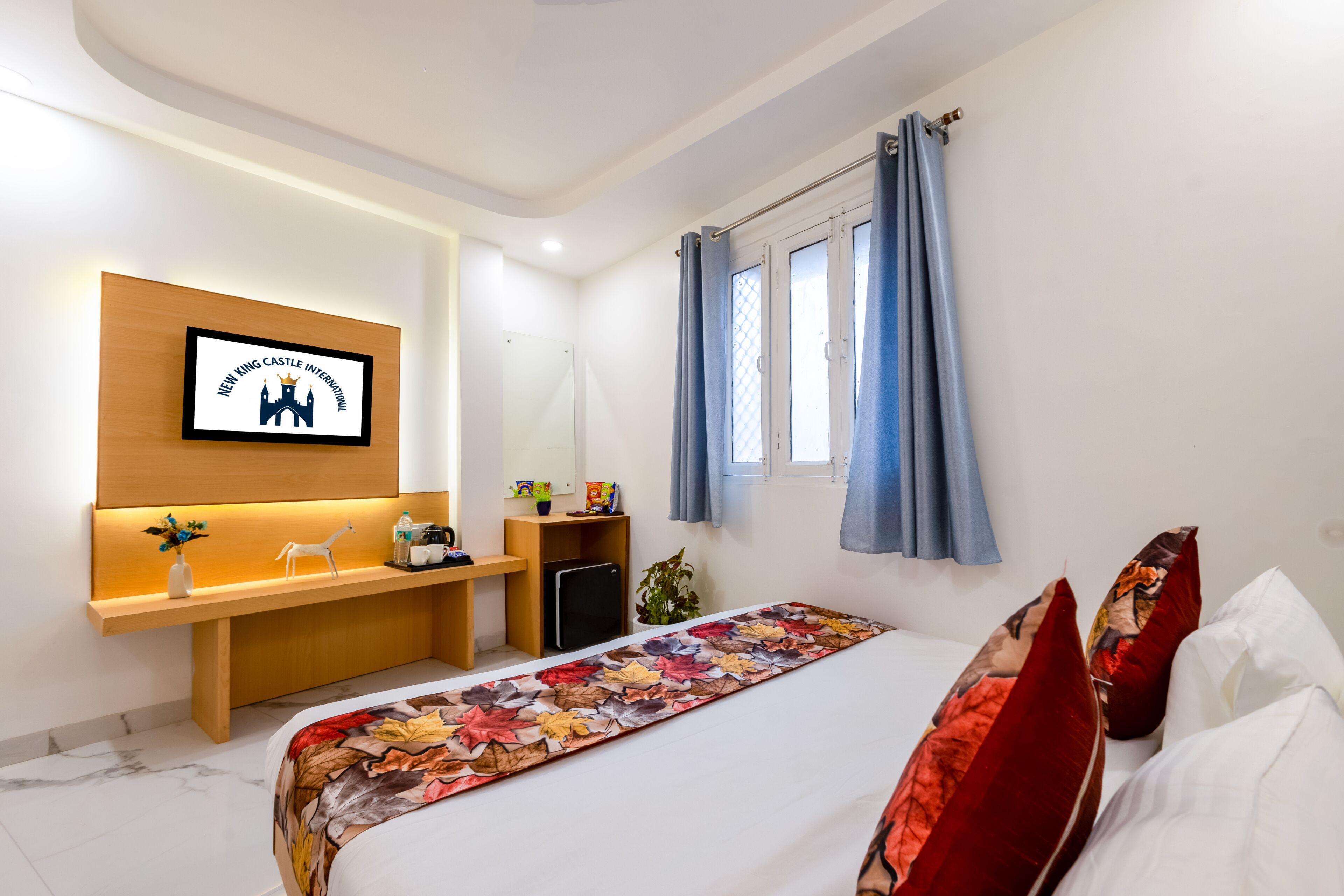 Een hotelkamer met een bed, een bureau, een televisie en een raam met gordijnen.