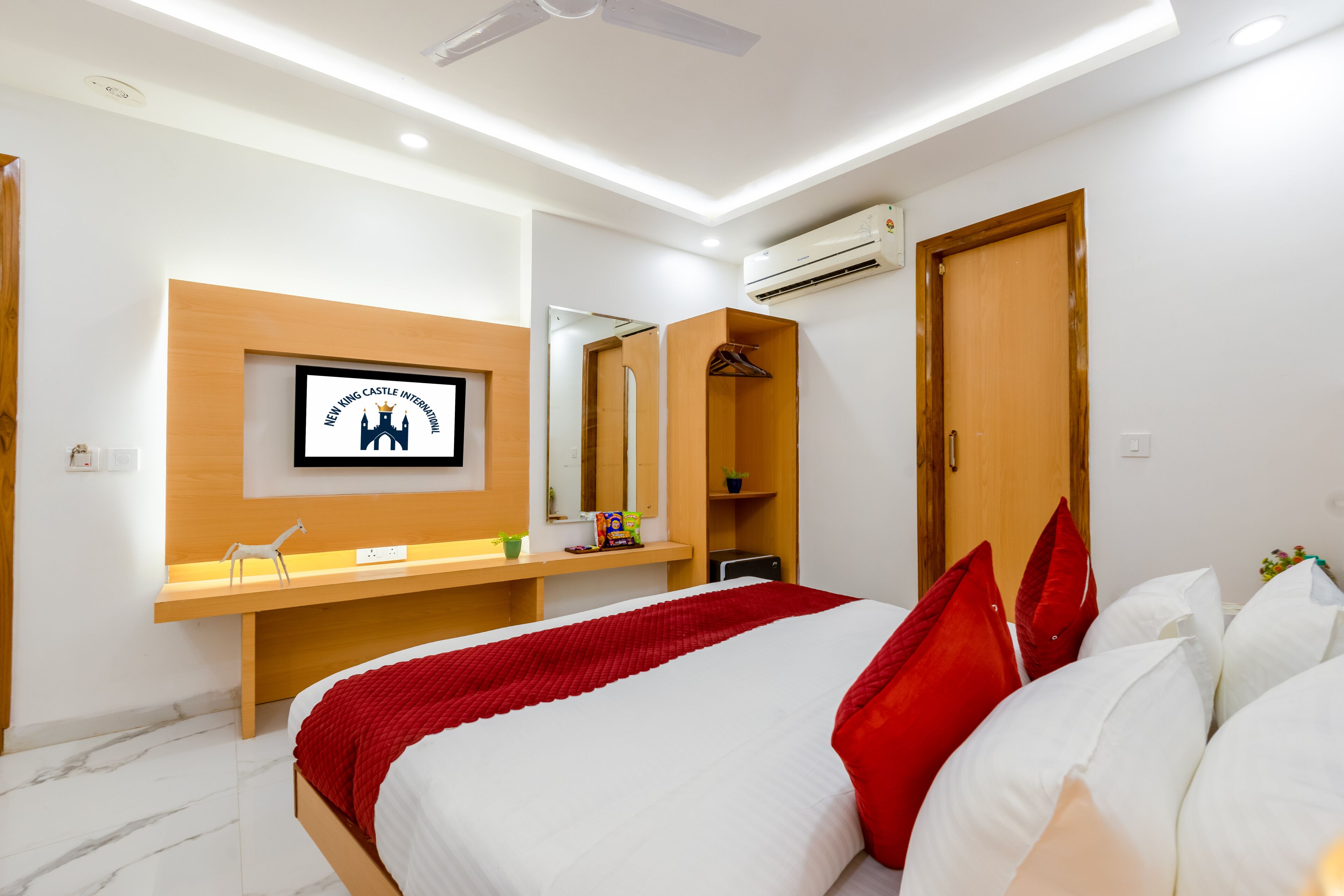 A modern bedroom with a bed, a desk, a mirror, and an air conditioning unit.