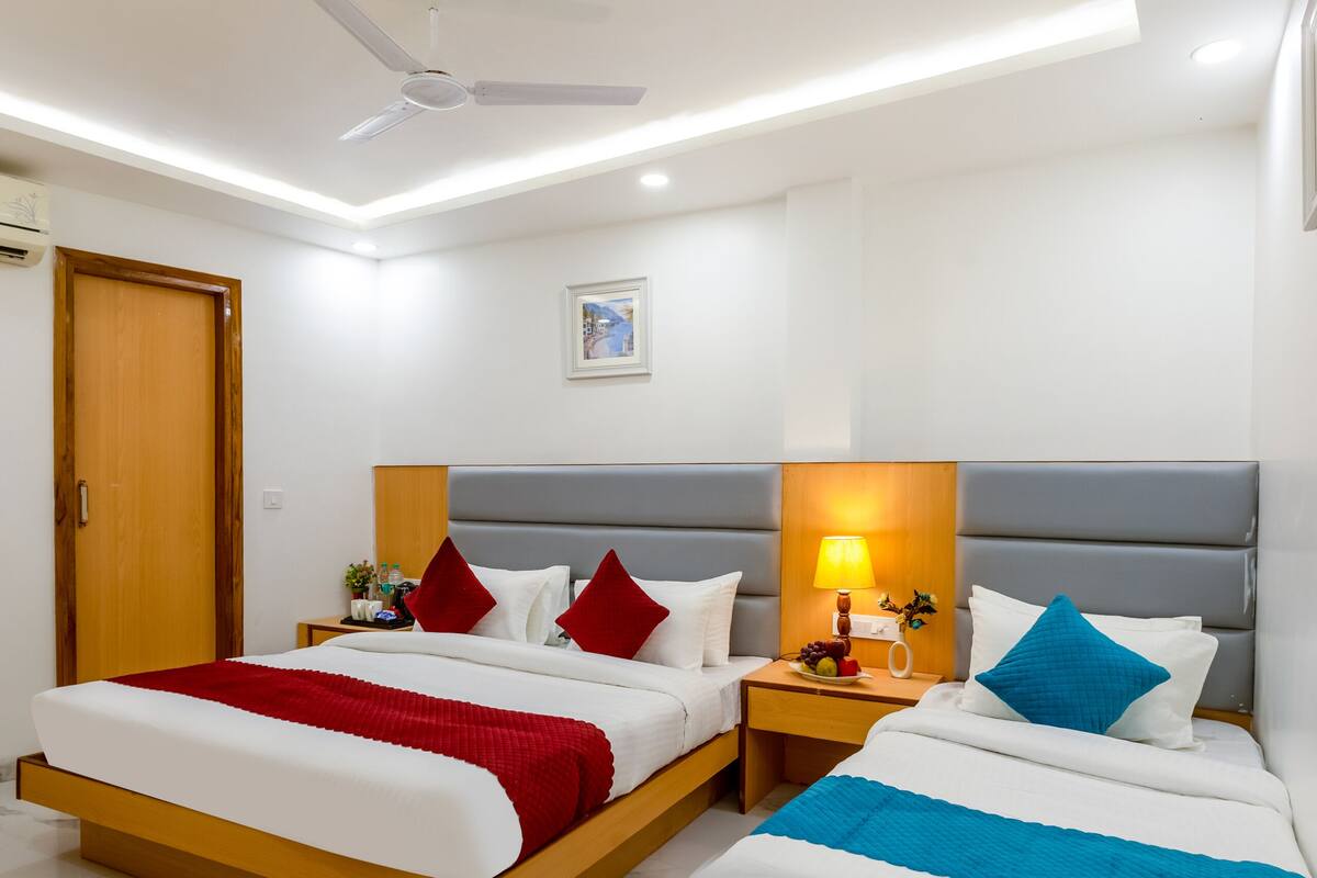 Ein Hotelzimmer mit zwei Betten, einem Deckenventilator, einem Nachttisch mit Lampe und einem Wandbild.