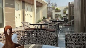 Un área de estar al aire libre con mobiliario de mimbre y una jardinera de madera.