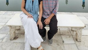 Una pareja sentada en un banco con el Taj Mahal al fondo.