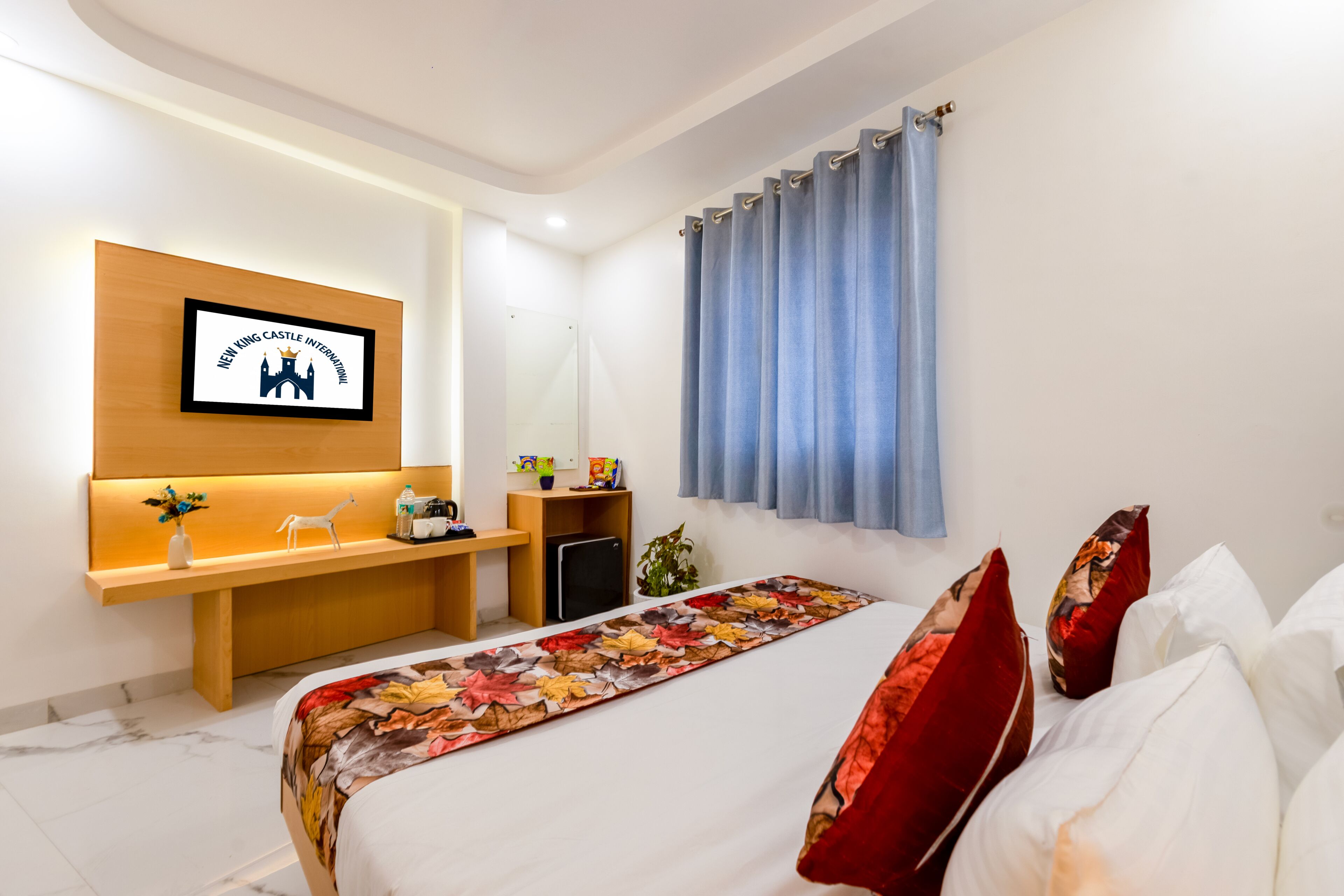 Hotellihuone, jossa on sänky, työpöytä, tuoli, televisio ja ikkuna, jossa on verhot.
