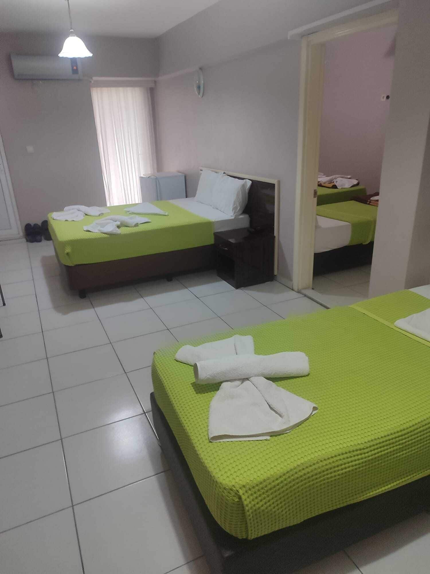 A hotel room with two beds, a bedside table, a chair, and an air conditioning unit.