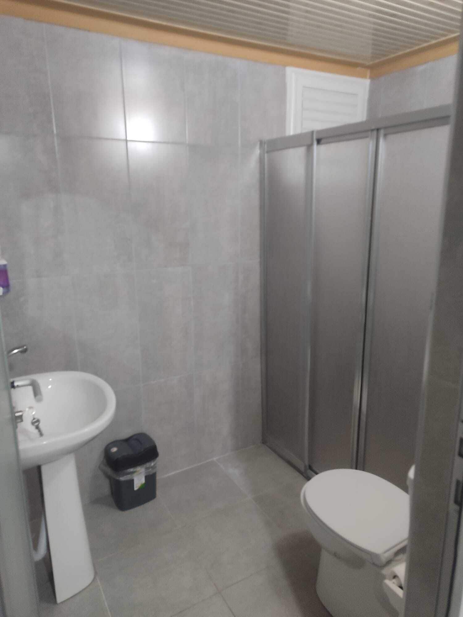 Un baño pequeño con lavamanos, inodoro y cabina de ducha.