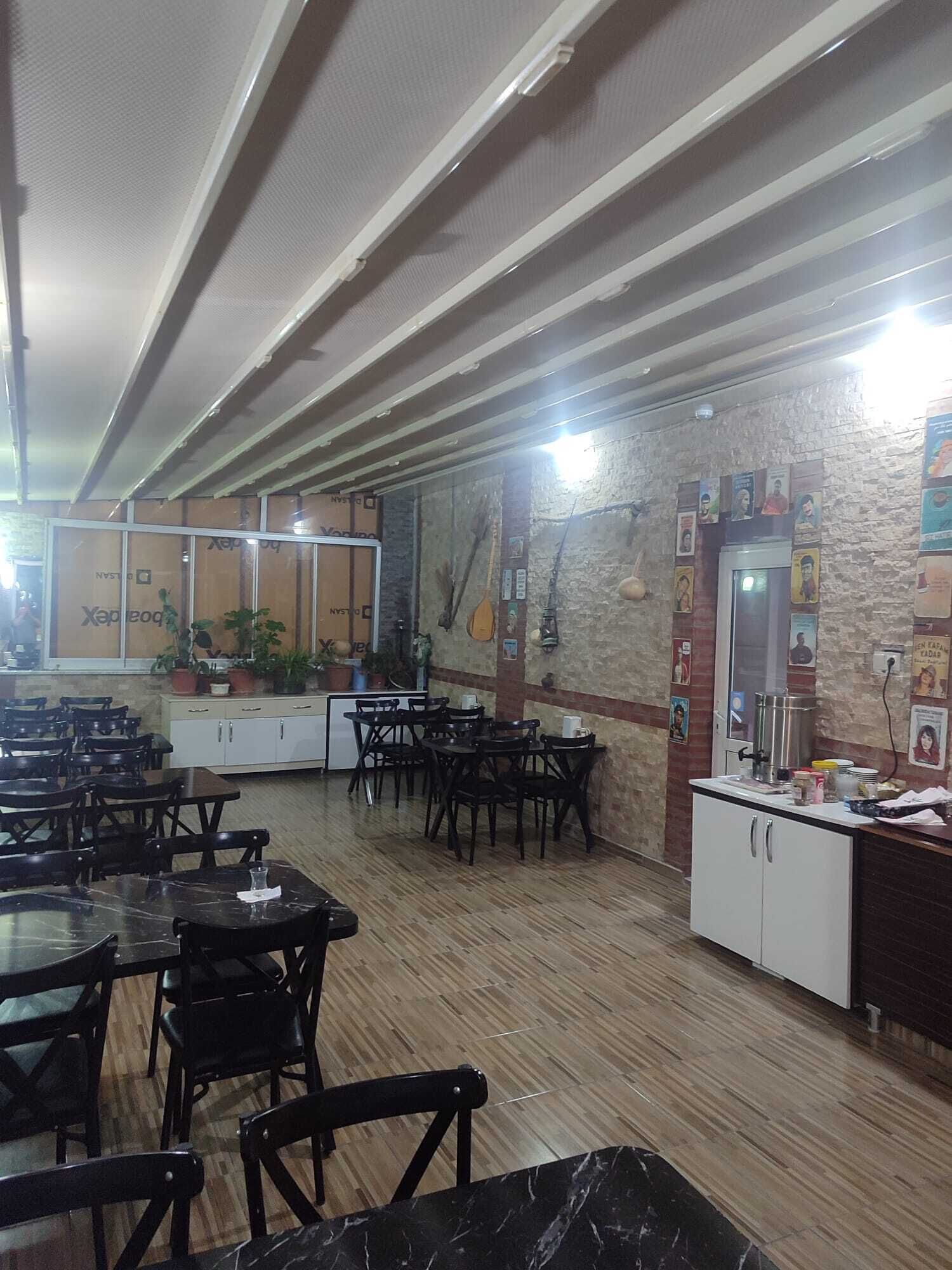 Un ristorante con pavimento in legno, sedie nere e una parete in pietra con manifesti.