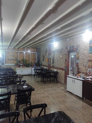 Un restaurante con suelo de madera, sillas negras y una pared de piedra decorada con carteles.