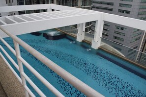 A rooftop pool with a hot tub, surrounded by a white railing and glass balustrades, overlooking a cityscape. - KLCC Parkview Residence Suites (Kuala Lumpur)