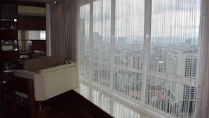 A modern living room with a large window, a sofa, and a bookshelf. - KLCC Parkview Residence Suites (Kuala Lumpur)