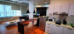 A modern kitchen with a dining area, built-in appliances, and a large window providing natural light. - KLCC Parkview Residence Suites (Kuala Lumpur)