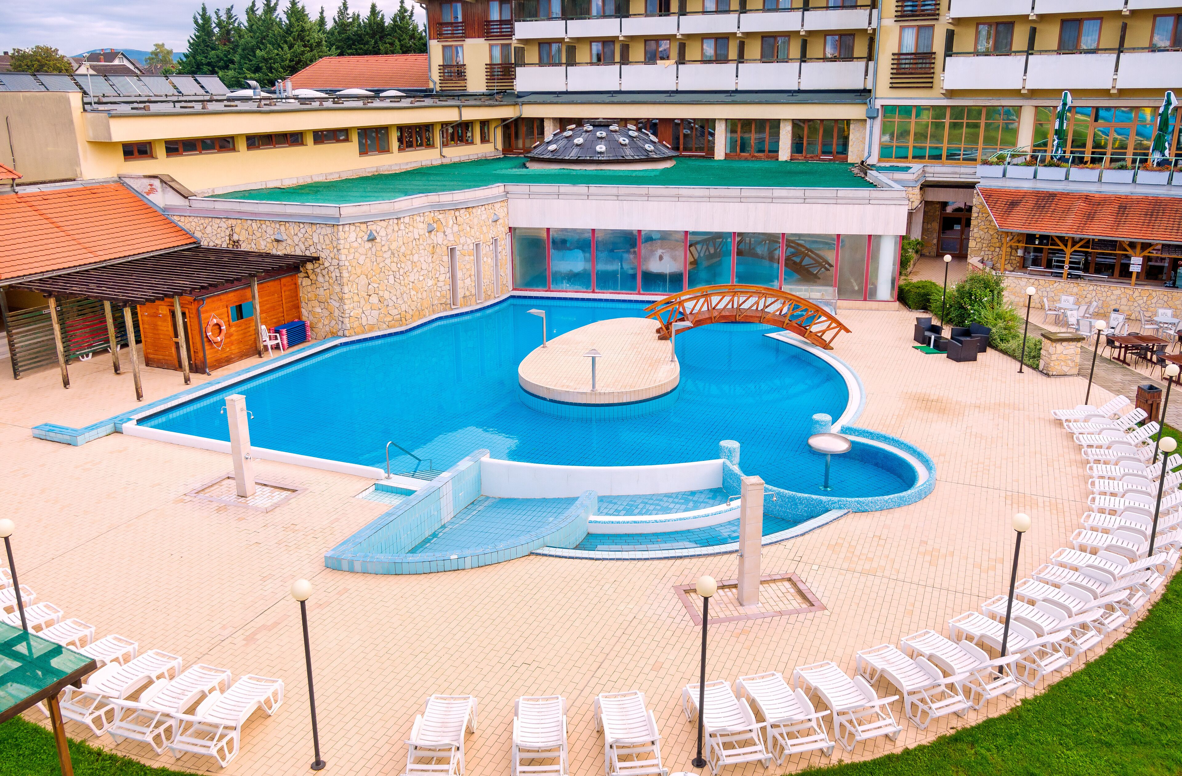 A swimming pool with a slide, surrounded by lounge chairs and a building with multiple floors.