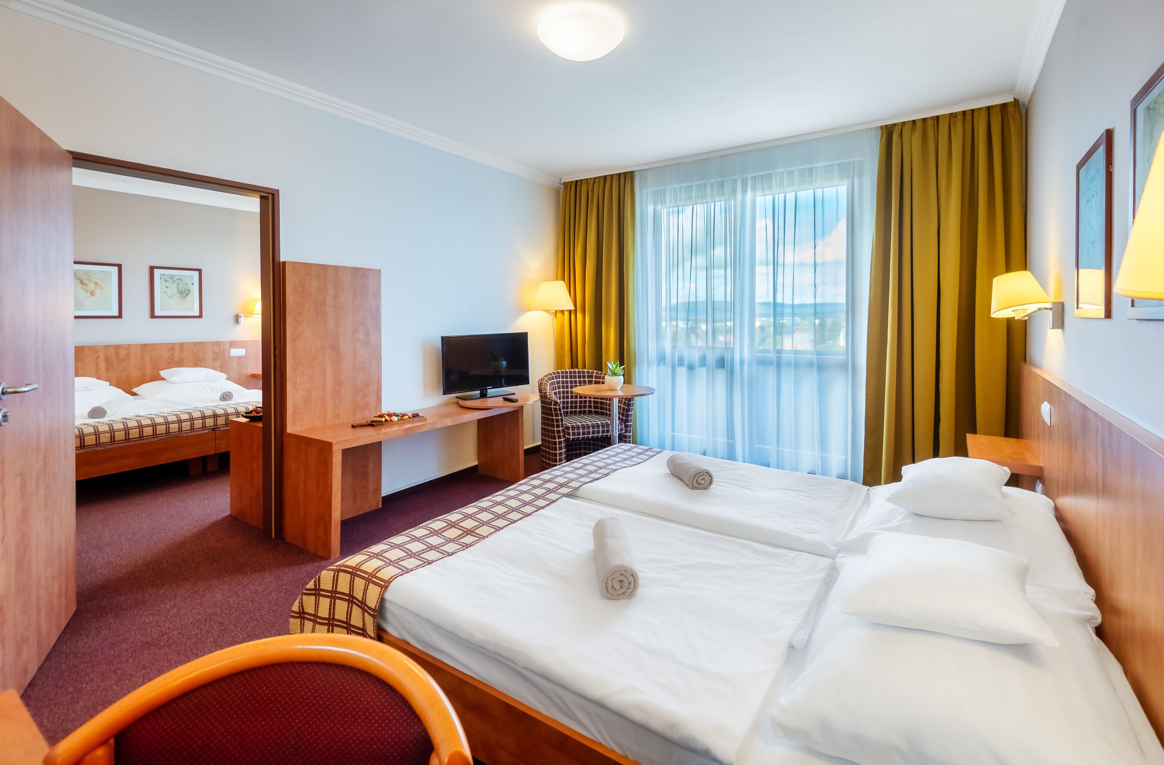 Habitación de hotel con dos camas, un escritorio, un televisor y vista al mar.