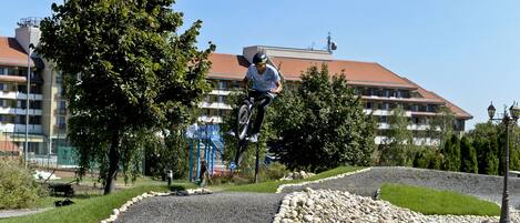 A person performing a trick on a BMX bike in an outdoor area with a building in the background.