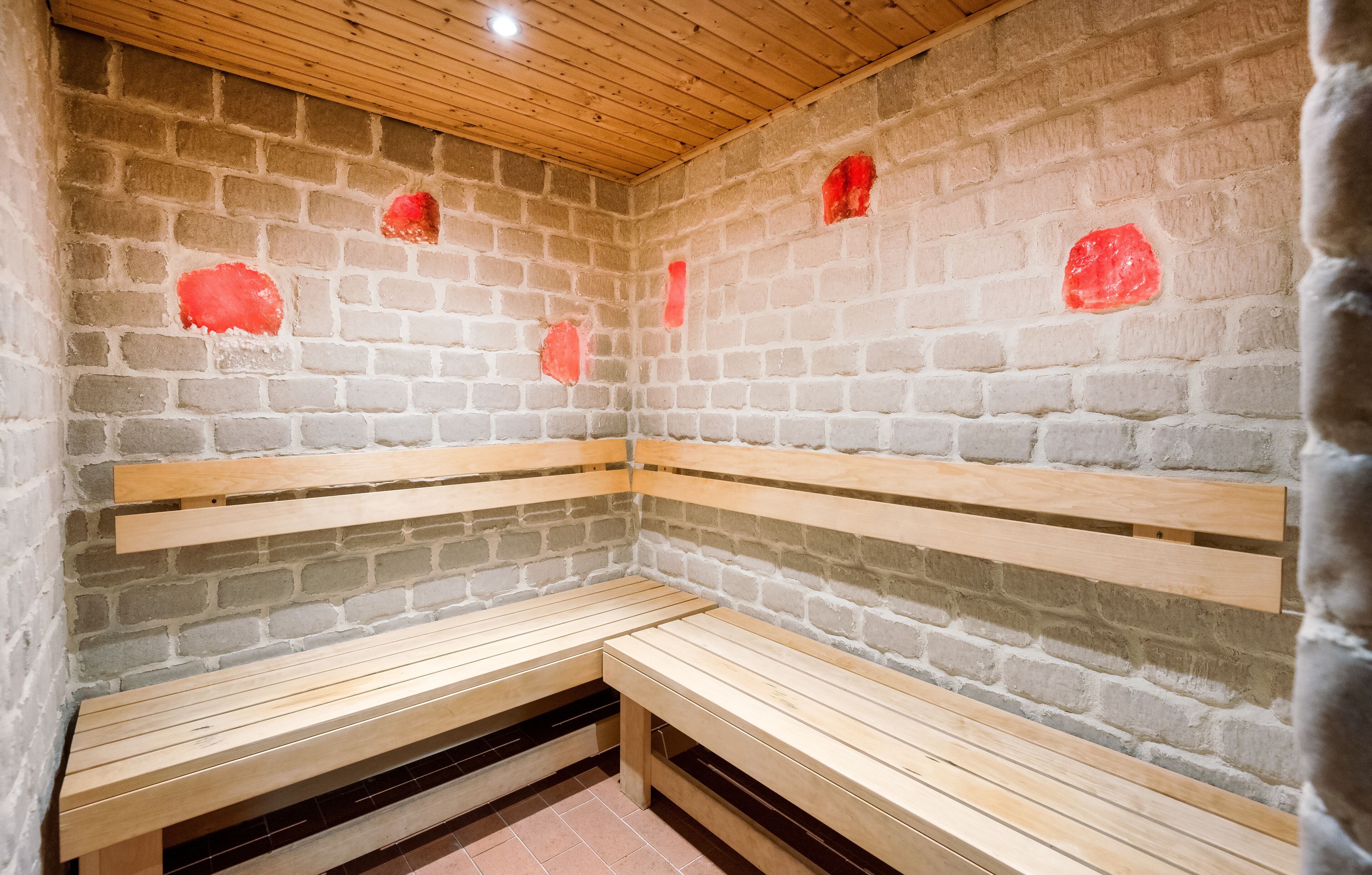 A sauna with wooden benches and brick walls.
