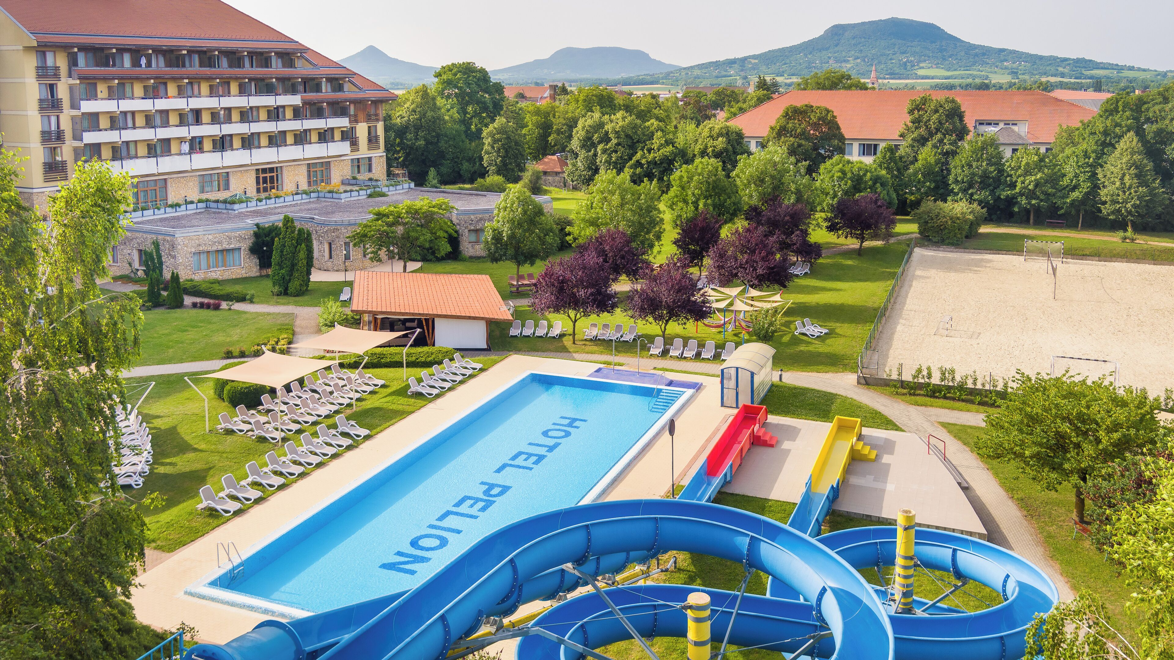 Un hotel con piscina, toboganes acuáticos y vistas de edificios y colinas circundantes.